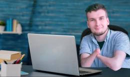 Smiling young man with no hands sitting at a computer. 